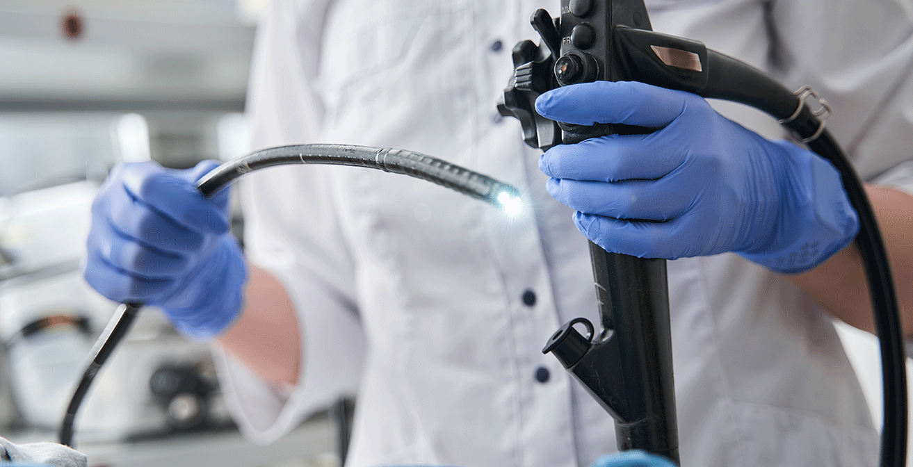 Doctor holding a flexible endoscope, preparing to examine a patient’s digestive tract.