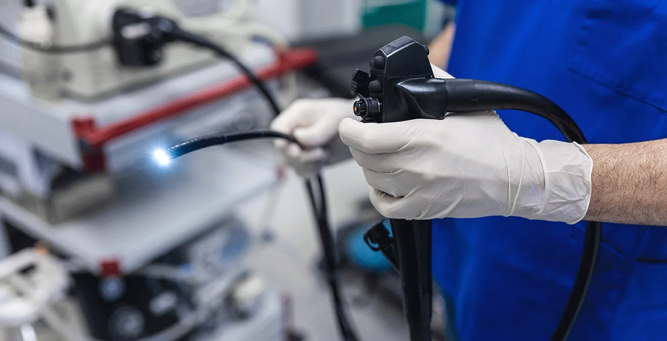 Doctor holding an endoscope during a colonoscopy procedure in a clinical setting.