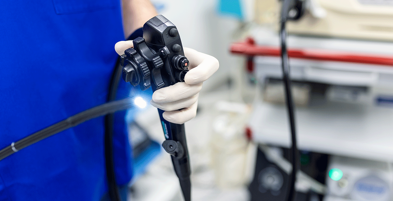 Medical professional holding an endoscope with light source visible, used for endoscopic procedures in a clinical setting.